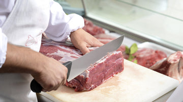 A butcher slices a custom steak behind his counter.