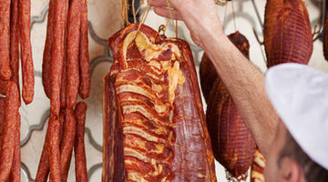 Male butcher hanging meat on hook in shop