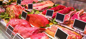 Assorted fresh beef cuts and sausages displayed at a butcher shop counter