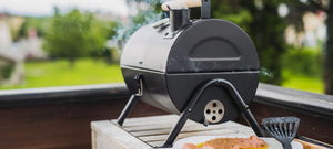 Compact backyard charcoal smoker grill producing smoke while cooking outdoors