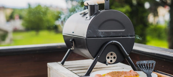 Compact backyard charcoal smoker grill producing smoke while cooking outdoors