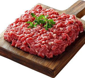 Fresh raw ground beef on a wooden cutting board garnished with herbs