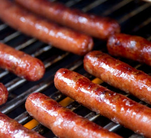 Hot dogs grilling on a barbecue grill with visible grill marks