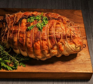Roasted turducken tied with butcher’s twine on a wooden cutting board
