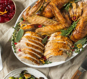 Sliced smoked turkey breast and whole smoked turkey garnished with herbs on a serving platter