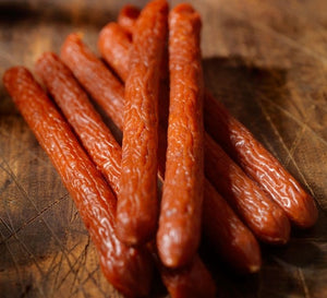 Smoked pepperoni snack sticks arranged on a wooden cutting board